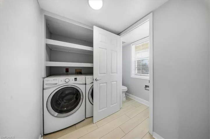 Laundry area featuring wood finish floors and washing machine and clothes dryer