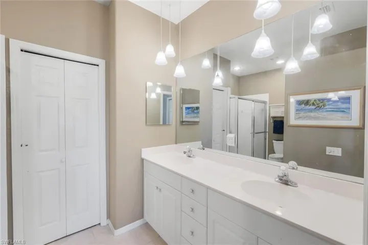Full bath with a closet, double vanity, a stall shower, and light tile patterned floors
