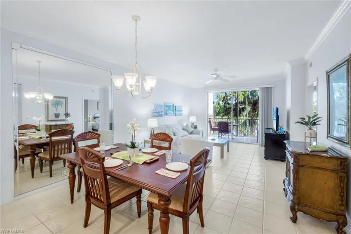 Dining space with crown molding, a ceiling fan, light tile patterned floors, and a chandelier
