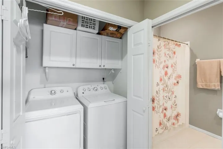 Washroom featuring cabinet space, separate washer and dryer, and light tile patterned floors