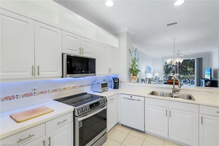 Kitchen with stainless steel appliances, white cabinets, light countertops, crown molding, and recessed lighting
