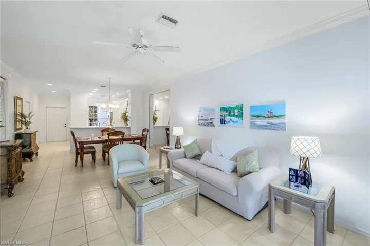 Living room with ornamental molding, light tile patterned floors, ceiling fan, recessed lighting, and a chandelier