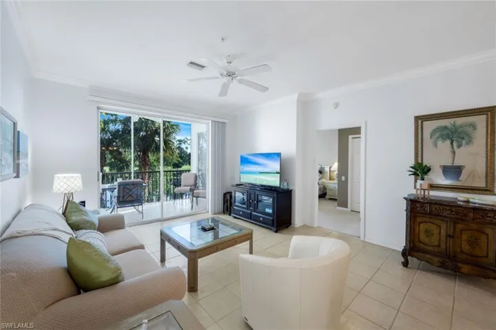 Tiled living area with ornamental molding and a ceiling fan