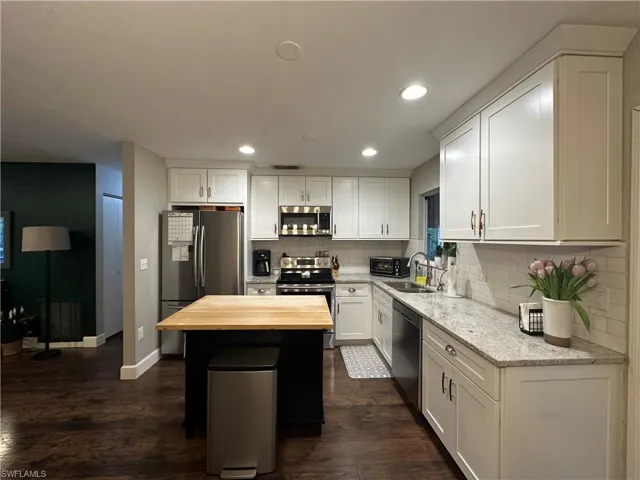 Kitchen featuring tasteful backsplash, white cabinets, a sink, wooden counters, and stainless steel appliances