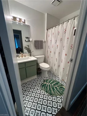 Bathroom with vanity, visible vents, toilet, a shower with shower curtain, and tile patterned floors