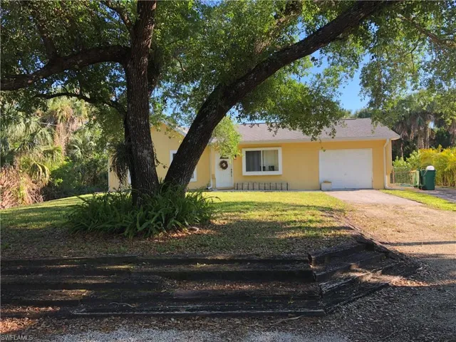 View of front of property featuring a garage, stucco siding, concrete driveway, and a front lawn