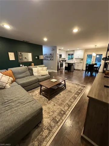 Living room featuring dark wood-style flooring, baseboards, and recessed lighting