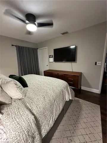 Bedroom featuring dark wood-type flooring, visible vents, baseboards, and ceiling fan