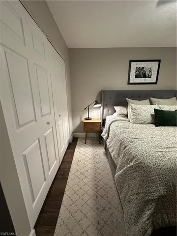 Bedroom with a closet, dark wood-style floors, and baseboards
