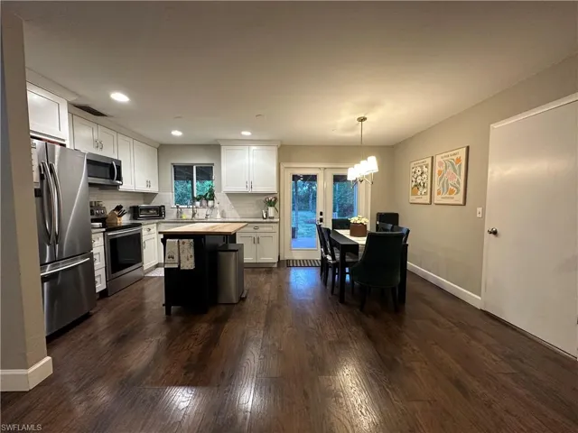 Kitchen featuring backsplash, white cabinetry, appliances with stainless steel finishes, light countertops, and dark wood-style floors
