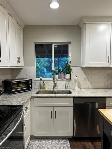 Kitchen featuring range, white cabinets, a sink, and dishwashing machine