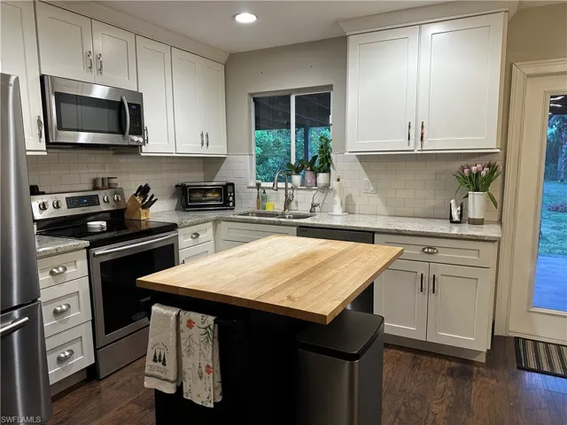 Kitchen with butcher block countertops, appliances with stainless steel finishes, a sink, and dark wood finished floors