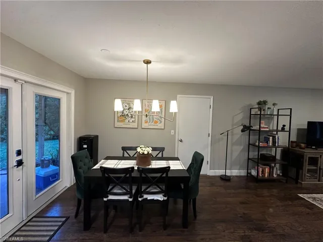Dining space featuring a chandelier, dark wood-style flooring, and baseboards
