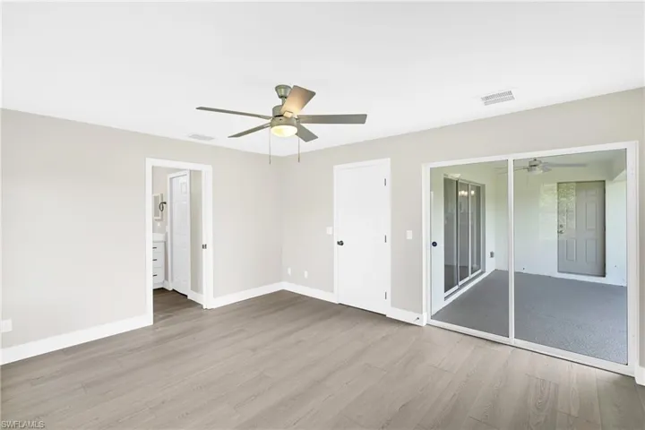 Spacious room featuring light wood-finish flooring, a contemporary ceiling fan, and light gray wall paint