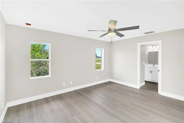 Spacious room featuring wood-finish flooring, light gray wall paint, and white baseboards