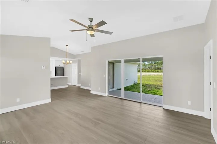 Spacious interior featuring wood-finish flooring, vaulted ceilings, and a ceiling fan with integrated lighting