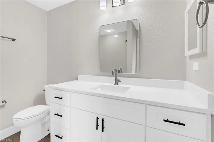Bathroom featuring a white vanity with integrated sink, brushed nickel faucet, and a wall-mounted mirror