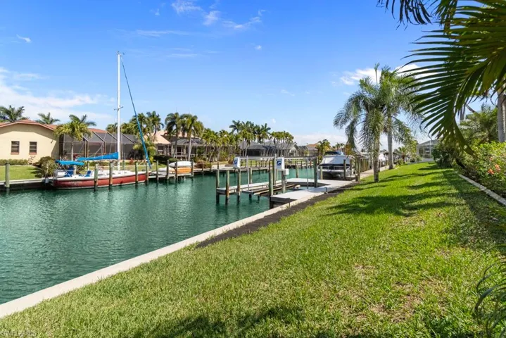 Dock featuring a water view, boat lift, a yard, and a residential view