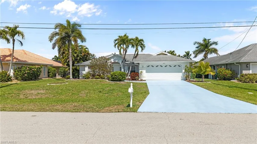 Ranch-style home with a front yard, a garage, concrete driveway, and stucco siding