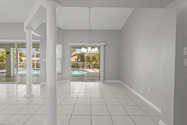 Unfurnished dining area featuring ornate columns, a textured wall, suspended lighting, and light tile patterned floors