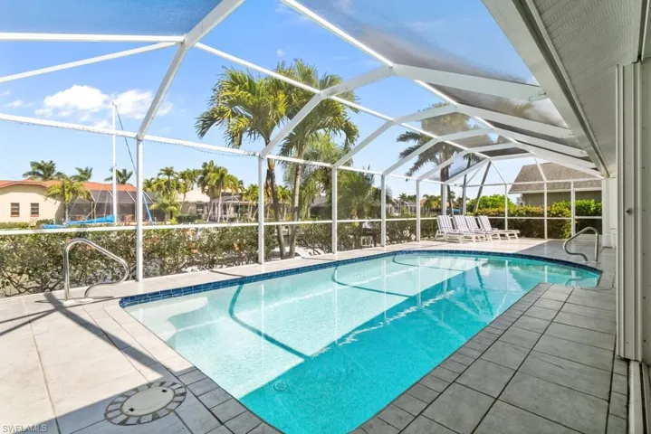 Swimming pool featuring a patio, a sunroom, and glass enclosure