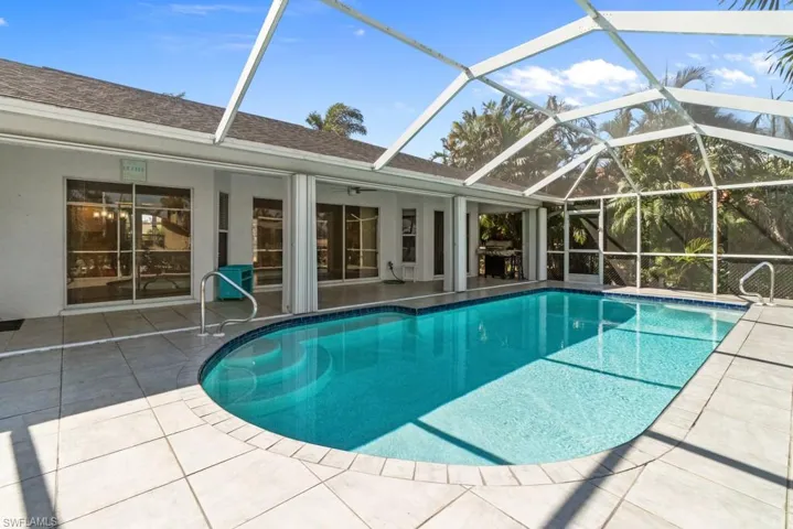 Outdoor pool featuring a sunroom, a patio, and glass enclosure
