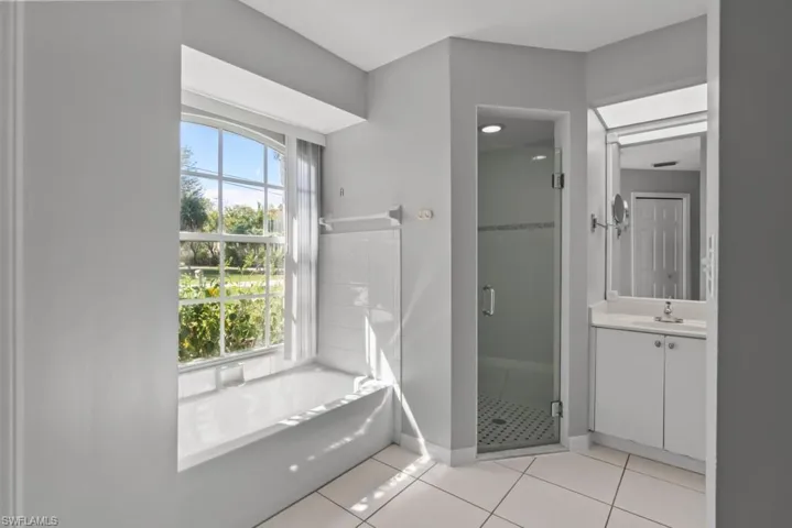 Master Bathroom featuring vanity, a shower stall, light tile patterned floors, and a bath