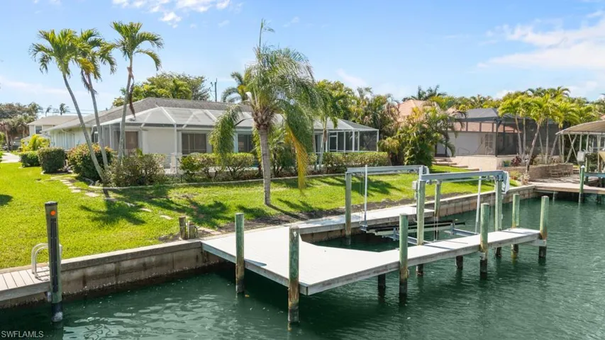 Dock area with a water view, a lanai, a yard, and boat lift