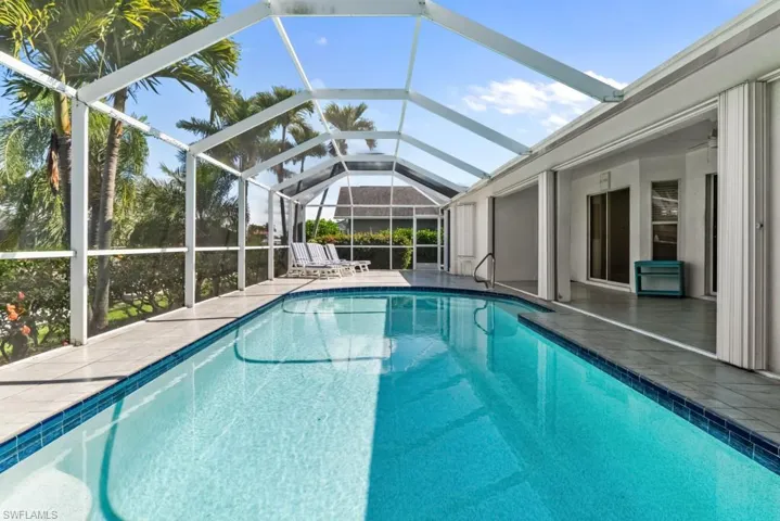 Swimming pool featuring a patio, a sunroom, and glass enclosure