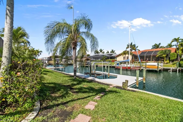 Dock area featuring boat lift, a lawn, and a water view