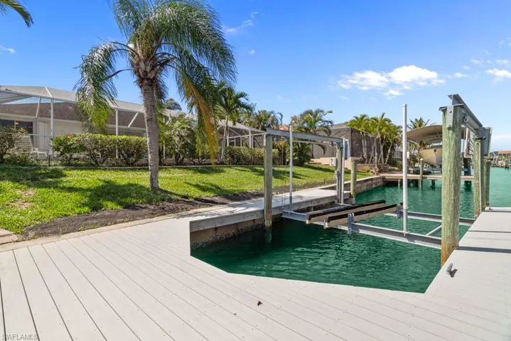 Dock with boat lift, a water view, and a yard