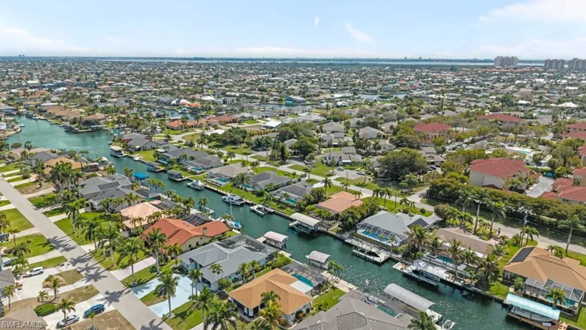 Aerial view of property and surrounding area featuring nearby suburban area and a large body of water