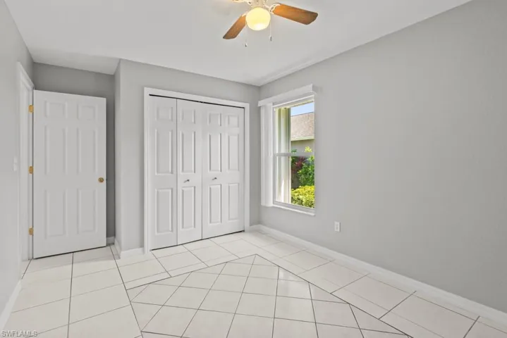 Unfurnished bedroom featuring light tile patterned flooring, a closet, and a ceiling fan