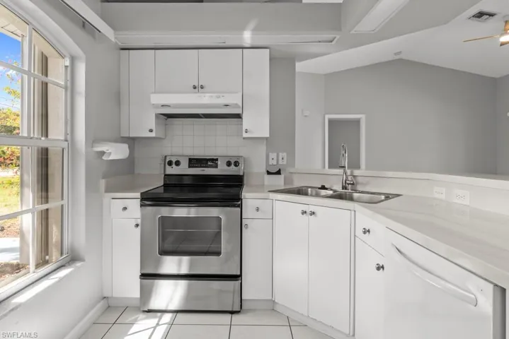 Kitchen with stainless steel electric range, white cabinetry, light countertops, decorative backsplash, and dishwasher