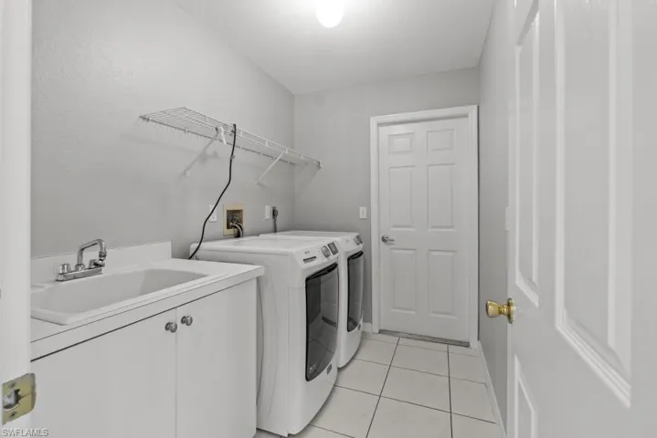 Laundry room featuring light tile patterned floors, independent washer and dryer, and cabinet space