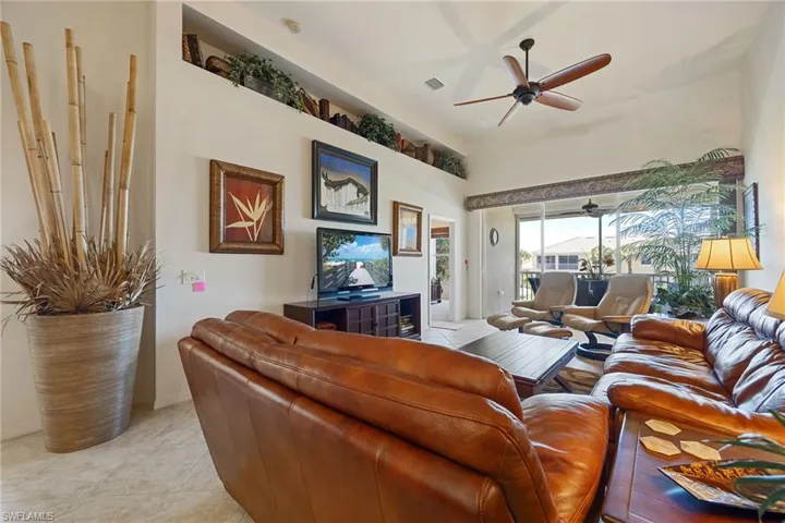 Living area featuring ceiling fan, light tile patterned floors, and a high ceiling