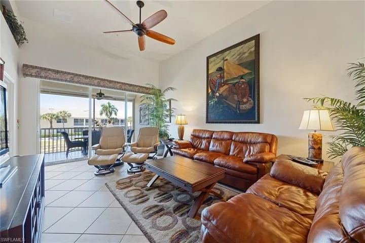 Tiled living room featuring a ceiling fan and a high ceiling