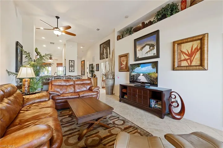 Living room featuring light tile patterned floors, a ceiling fan, and a high ceiling