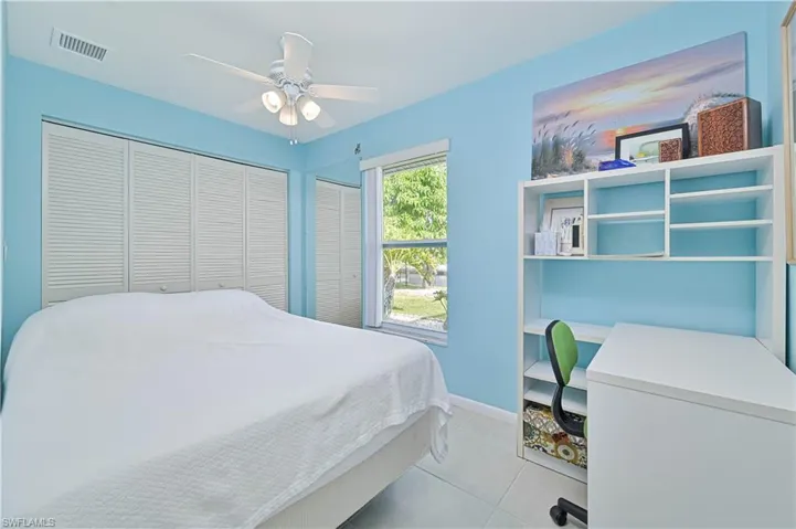 Bedroom featuring light tile patterned flooring, a closet, ceiling fan, and an office area