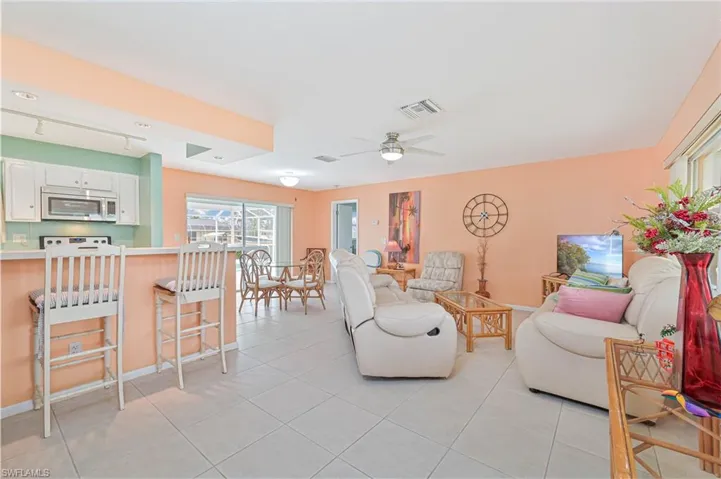 Living room with light tile patterned floors, ceiling fan, and rail lighting