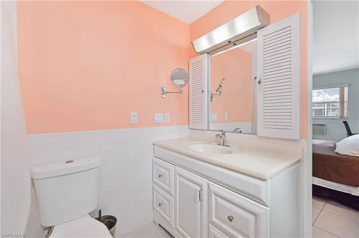 Ensuite bathroom with vanity, a wainscoted wall, light tile patterned flooring, and tile walls