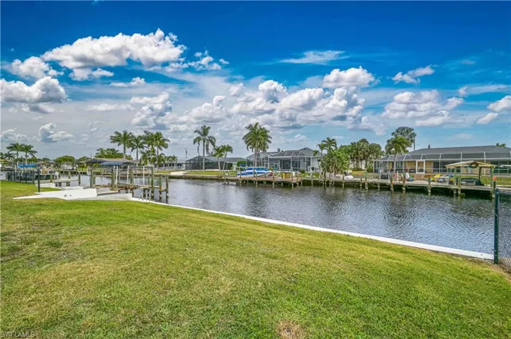 Dock area featuring a yard, a water view, boat lift, and a residential view