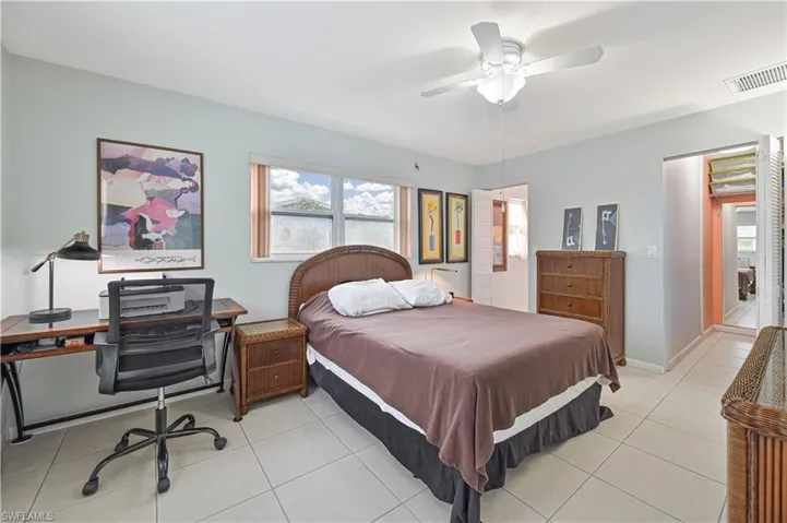 Bedroom featuring ceiling fan, an office area, and light tile patterned floors