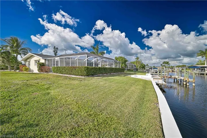Dock area with a lawn, a lanai, a sunroom, and boat lift