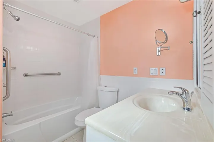 Bathroom with vanity, shower / bath combo with shower curtain, a wainscoted wall, and light tile patterned floors