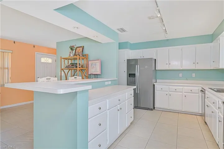 Kitchen featuring white cabinets, light countertops, light tile patterned flooring, and appliances with stainless steel finishes
