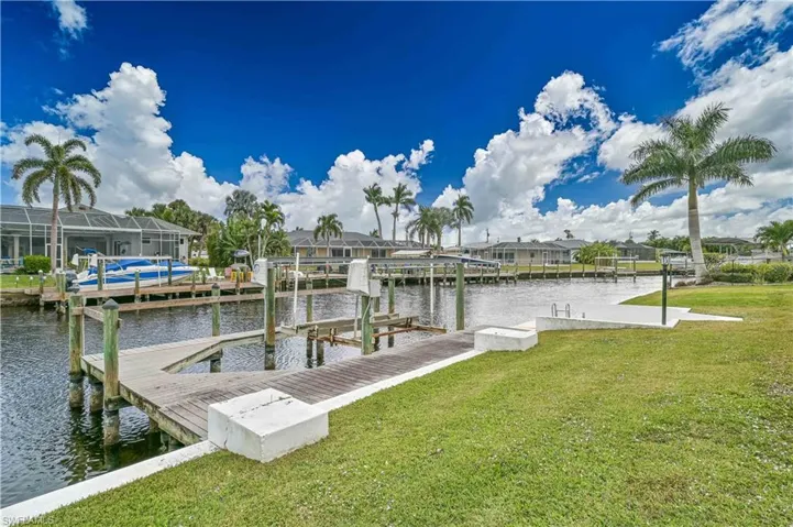 Dock area featuring boat lift, a residential view, a water view, and a lawn