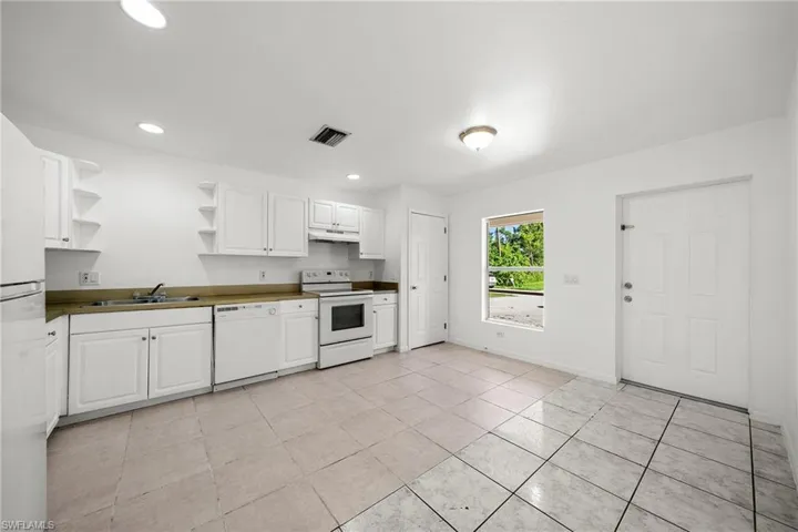 Kitchen featuring open shelves, white cabinetry, white appliances, dark countertops, and recessed lighting