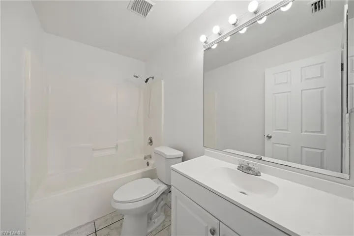 Bathroom with vanity, shower / bathtub combination, and light tile patterned flooring