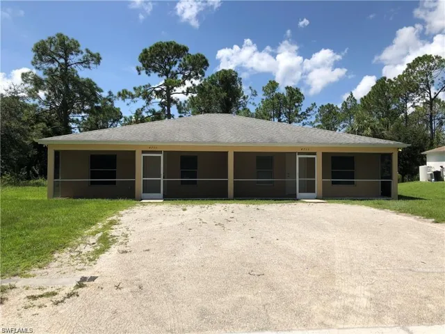View of front of house featuring a sunroom, driveway, a front lawn, and stucco siding